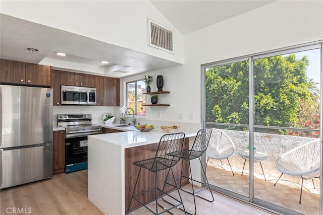 280 S Avenida Caballeros Unit 271, Palm Springs, CA 92262 - kitchen featuring appliances with stainless steel finishes, light countertops, a peninsula, open shelves, and a breakfast bar
