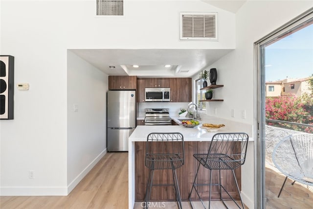 280 S Avenida Caballeros Unit 271, Palm Springs, CA 92262 - kitchen with stainless steel appliances, light countertops, a peninsula, a breakfast bar area, and light wood-type flooring