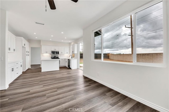 29605 Camino Cristal, Menifee, CA 92584 - interior space with stainless steel microwave, baseboards, white cabinetry, wood finished floors, and ceiling fan