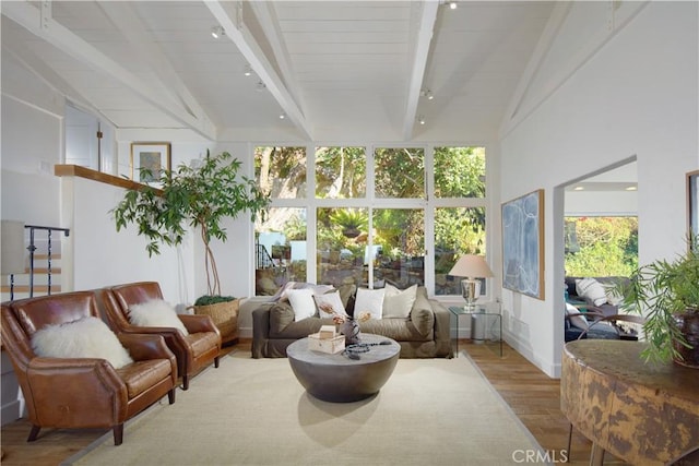 sunroom / solarium with wood finished floors, high vaulted ceiling, and beam ceiling