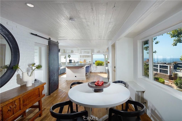 dining space featuring a barn door, recessed lighting, light wood finished floors, and wooden ceiling