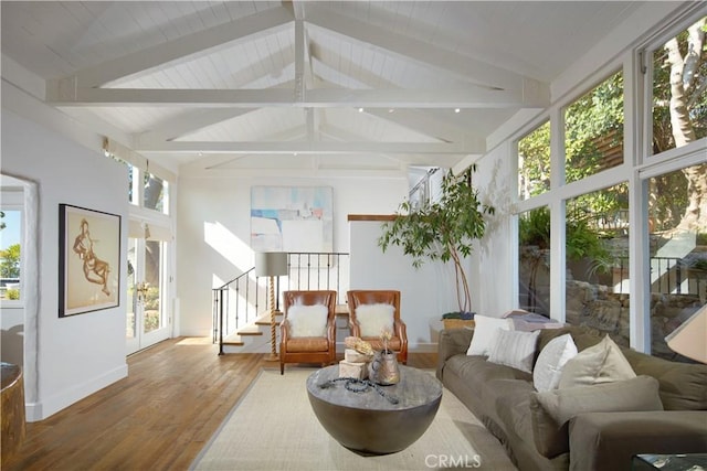 living area featuring wood finished floors, baseboards, vaulted ceiling with beams, and stairway