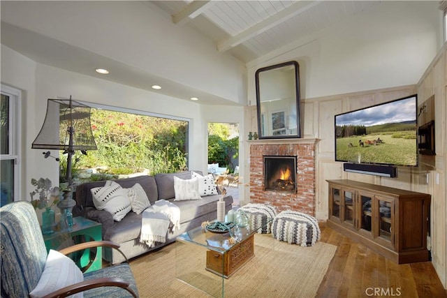 living area featuring high vaulted ceiling, beamed ceiling, a fireplace, recessed lighting, and hardwood / wood-style floors
