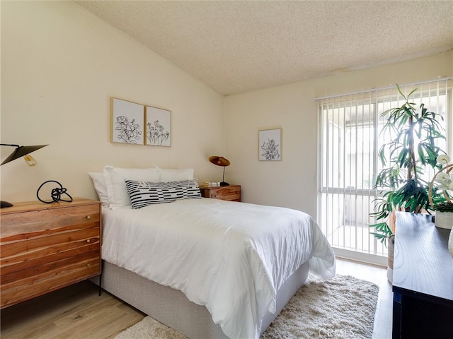 13061 Oak Hill Dr Unit 221B, Seal Beach, CA 90740 - bedroom featuring access to outside, a textured ceiling, vaulted ceiling, and wood finished floors