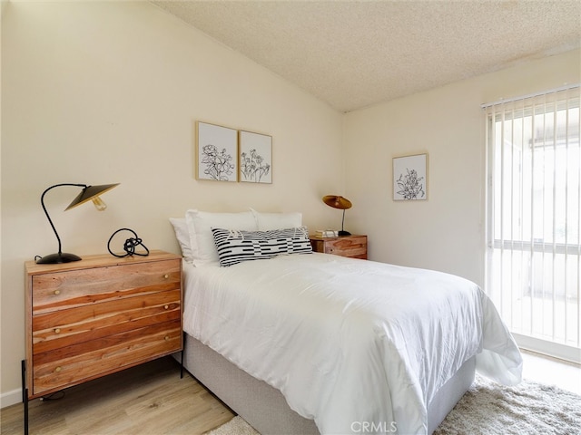 13061 Oak Hill Dr Unit 221B, Seal Beach, CA 90740 - bedroom featuring light wood finished floors, vaulted ceiling, and a textured ceiling
