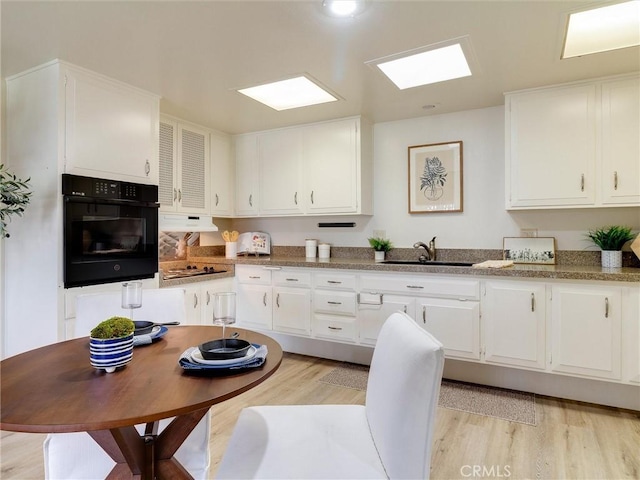 13061 Oak Hill Dr Unit 221B, Seal Beach, CA 90740 - kitchen with light wood-style flooring, oven, a sink, and white cabinets