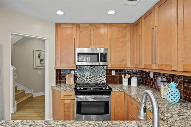 kitchen featuring light stone countertops, stainless steel appliances, and backsplash