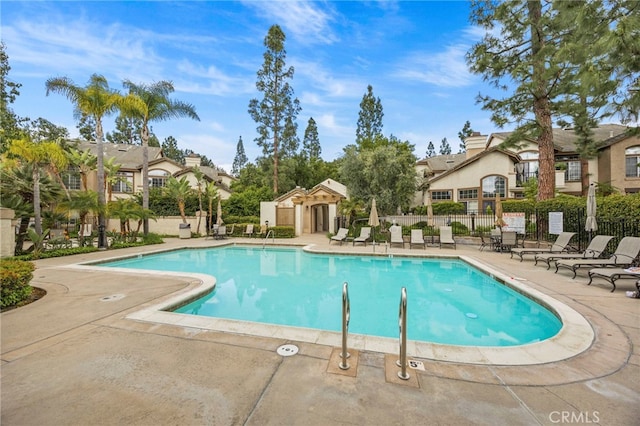 community pool featuring a residential view, a patio, and fence