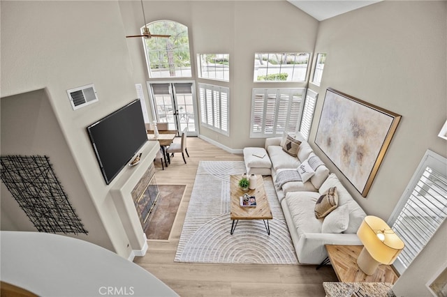living room featuring baseboards, wood finished floors, a towering ceiling, and visible vents