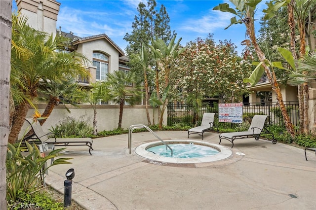 view of pool featuring fence, a community hot tub, and a patio
