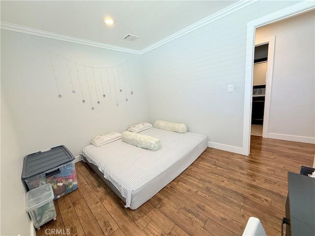 bedroom featuring crown molding, baseboards, visible vents, and hardwood / wood-style flooring