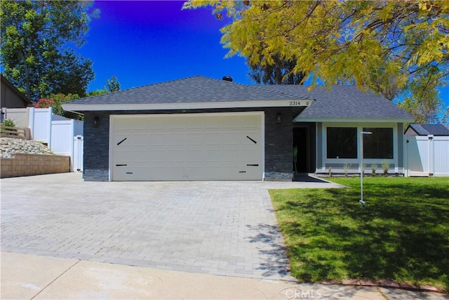 ranch-style house with a garage, a front lawn, fence, decorative driveway, and a shingled roof