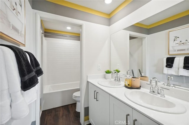 full bath featuring toilet, wood finished floors, double vanity, and a sink