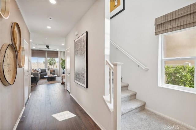 hallway with dark wood-type flooring, stairs, baseboards, and recessed lighting