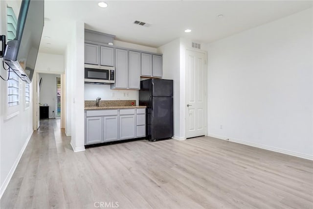 17963 Passionflower Ln, San Bernardino, CA 92407 - kitchen featuring freestanding refrigerator, stainless steel microwave, gray cabinets, light wood finished floors, and baseboards