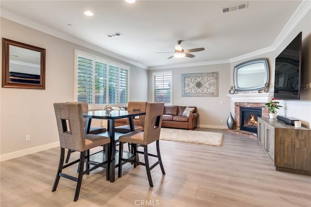 17963 Passionflower Ln, San Bernardino, CA 92407 - dining space with a ceiling fan, light wood-style flooring, crown molding, a fireplace, and baseboards