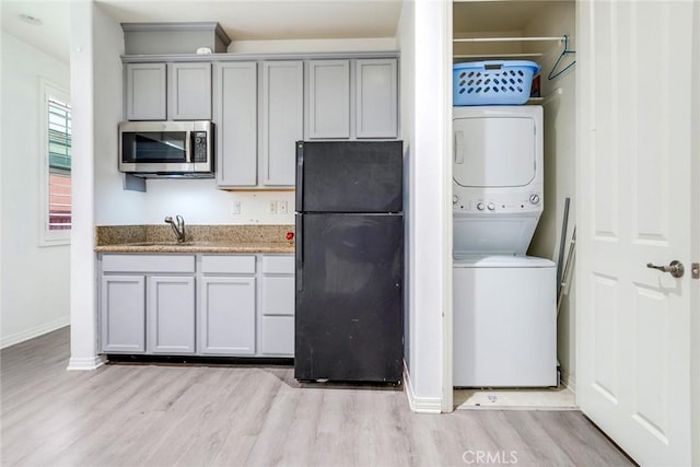 17963 Passionflower Ln, San Bernardino, CA 92407 - kitchen featuring freestanding refrigerator, estacked washer and dryer, stainless steel microwave, and gray cabinets