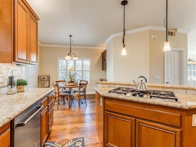 kitchen with stainless steel appliances, visible vents, ornamental molding, light wood-style floors, and brown cabinetry