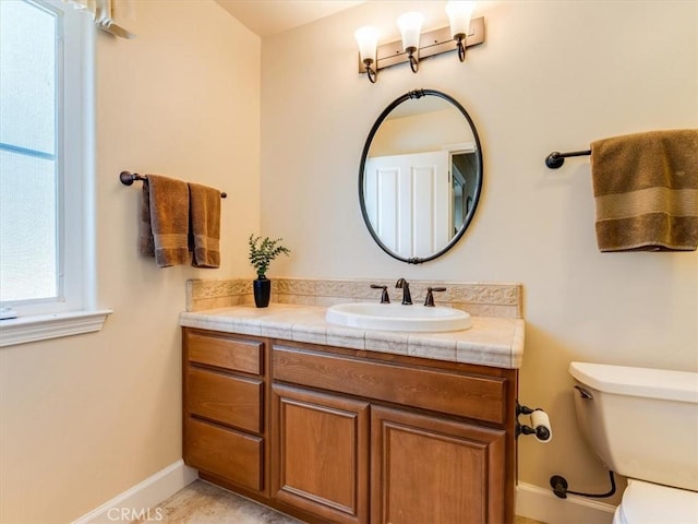 bathroom with baseboards, toilet, and vanity