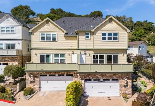 rear view of house featuring an attached garage, stone siding, and driveway