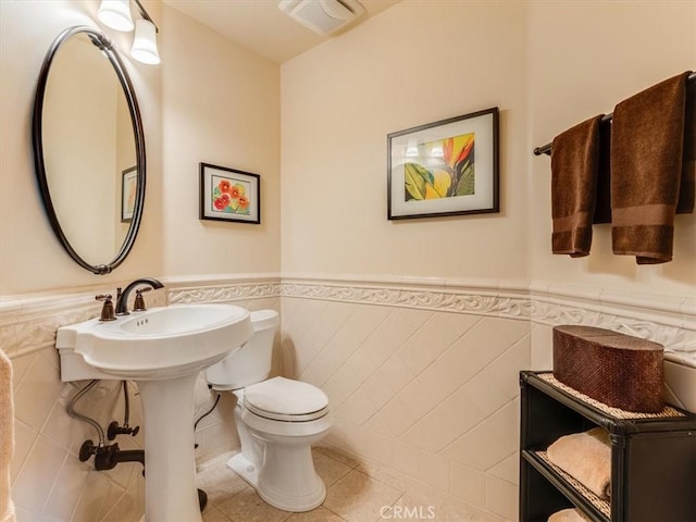 bathroom with wainscoting, toilet, tile patterned flooring, and visible vents
