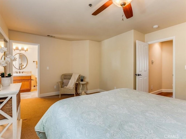 bedroom featuring ceiling fan, light carpet, baseboards, ensuite bath, and visible vents