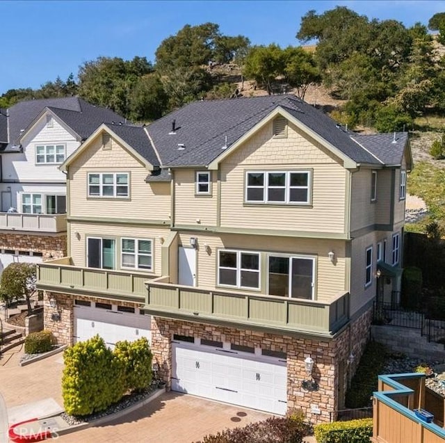 townhome / multi-family property featuring stone siding, decorative driveway, and a garage