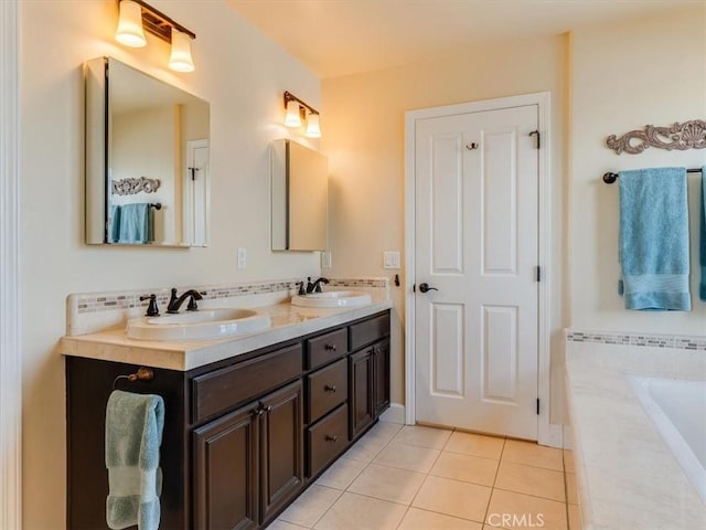 full bath featuring double vanity, tile patterned floors, a relaxing tiled tub, and a sink