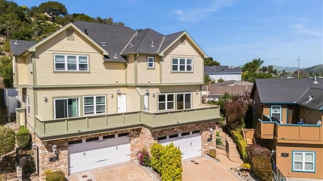 multi unit property with stone siding, an attached garage, and driveway