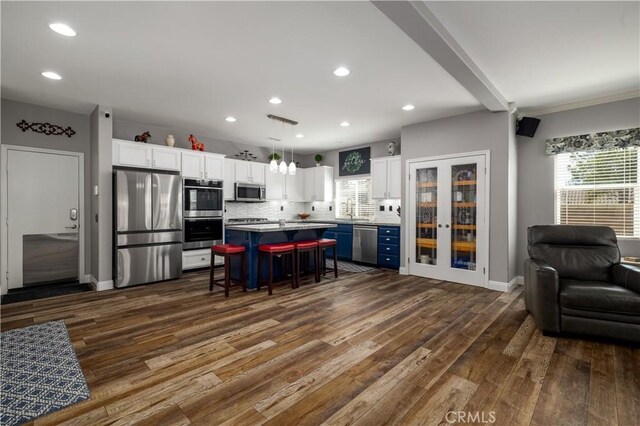 29465 Siderite Cir, Menifee, CA 92584 - kitchen featuring appliances with stainless steel finishes, open floor plan, a breakfast bar, white cabinets, and dark wood finished floors
