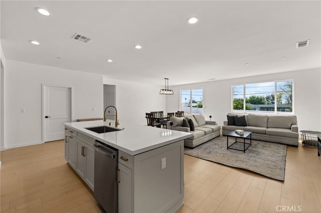 kitchen with gray cabinetry, dishwasher, a sink, and visible vents