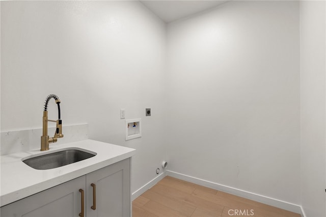clothes washing area with hookup for an electric dryer, washer hookup, light wood-style floors, cabinet space, and a sink