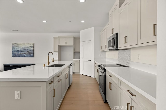 kitchen with light wood-style floors, appliances with stainless steel finishes, a sink, and recessed lighting