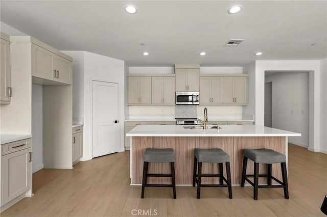kitchen featuring visible vents, a sink, light countertops, light wood-type flooring, and stainless steel microwave