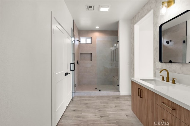 full bath with a shower stall, vanity, visible vents, and wood finished floors