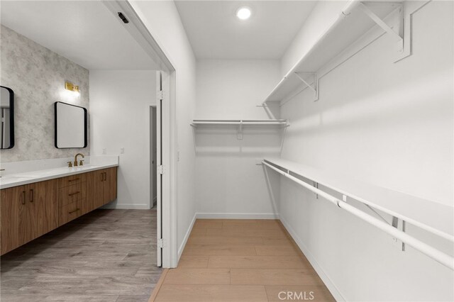 spacious closet with a sink and light wood-style floors
