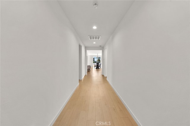 hallway featuring light wood-style flooring, baseboards, visible vents, and recessed lighting
