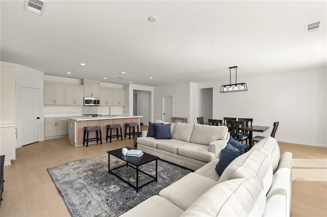 living room featuring light wood-style floors, recessed lighting, and visible vents