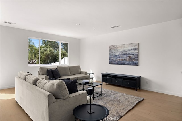 living area featuring wood finished floors, baseboards, and visible vents