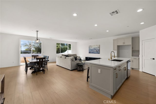 kitchen featuring visible vents, a sink, light countertops, a kitchen island with sink, and recessed lighting