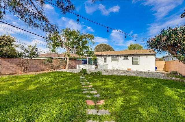 rear view of property featuring a yard, a fenced backyard, stucco siding, and a patio area