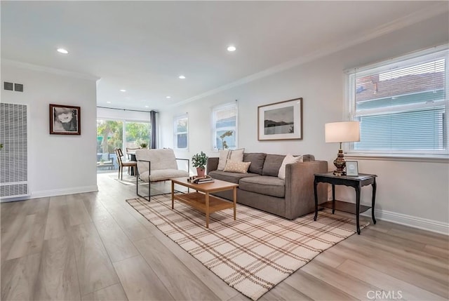 living area with crown molding, light wood finished floors, baseboards, and visible vents