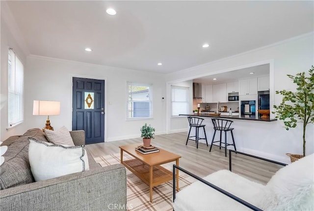 living area with recessed lighting, light wood finished floors, baseboards, and crown molding