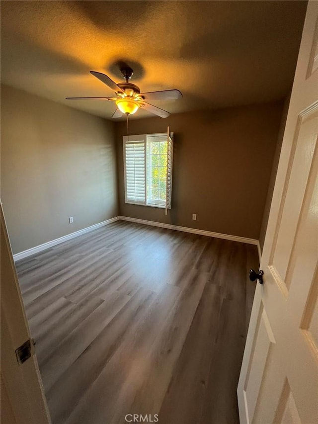 spare room with a textured ceiling, baseboards, a ceiling fan, and wood finished floors