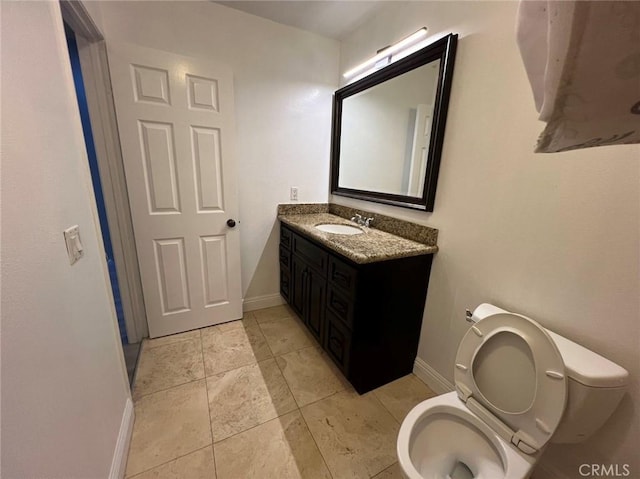 bathroom featuring toilet, vanity, baseboards, and tile patterned flooring