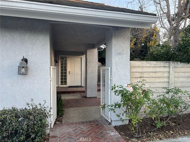 entrance to property with fence and stucco siding