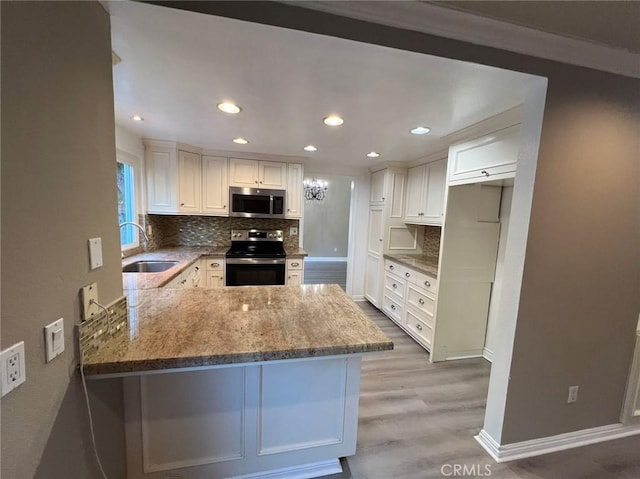 kitchen featuring a sink, appliances with stainless steel finishes, wood finished floors, light stone countertops, and backsplash