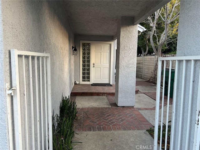 entrance to property featuring fence and stucco siding