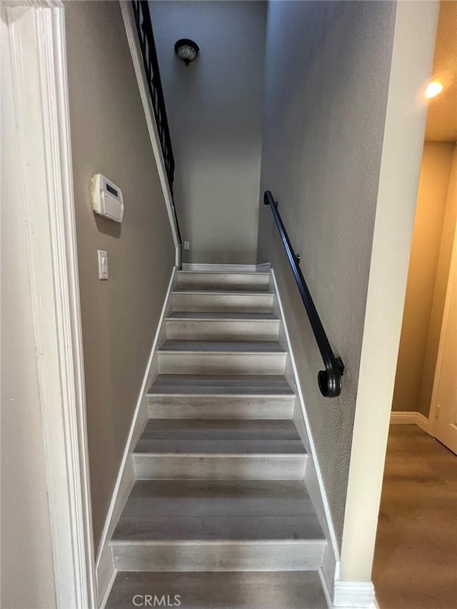 staircase with baseboards and wood finished floors