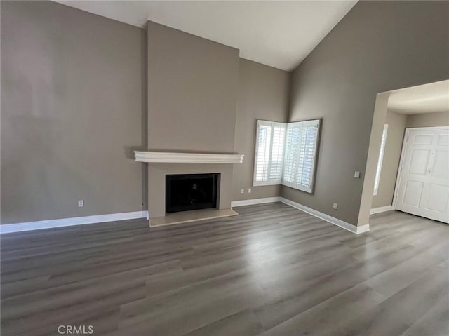 unfurnished living room with high vaulted ceiling, a fireplace, baseboards, and wood finished floors